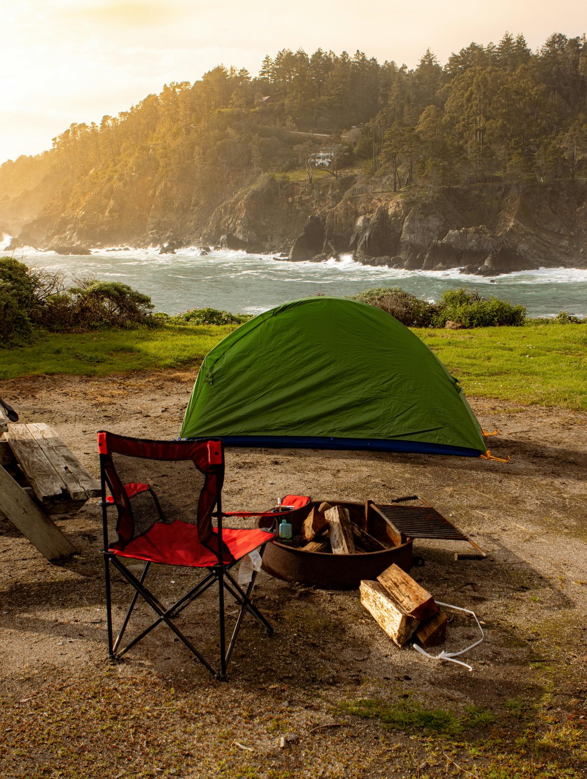 Serene camping site with a green tent and ocean view at Jenner, CA during sunset.