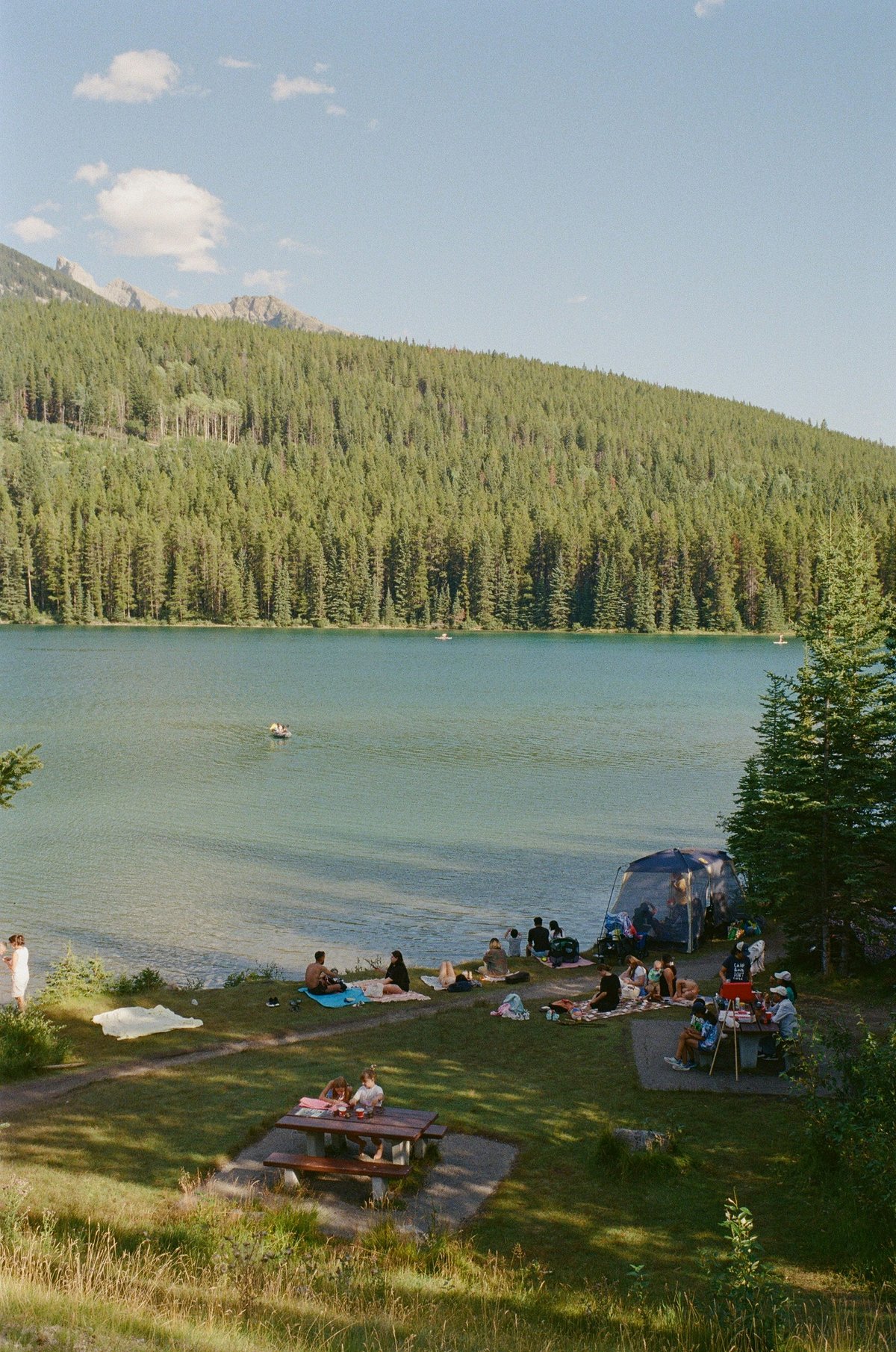 A group of people sitting at a picnic table next to a lake