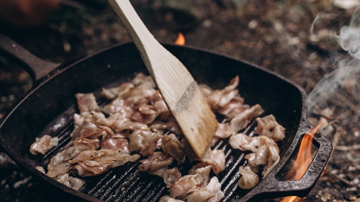 Cast iron skillet cooking over outdoor campfire